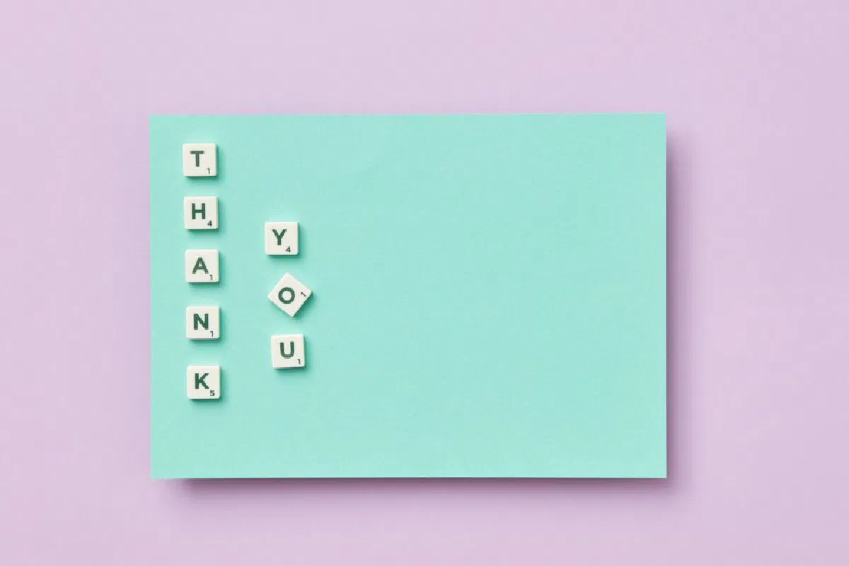 Scrabble tiles arranged to say 'Thank You' on a pastel background, ideal for greeting cards.