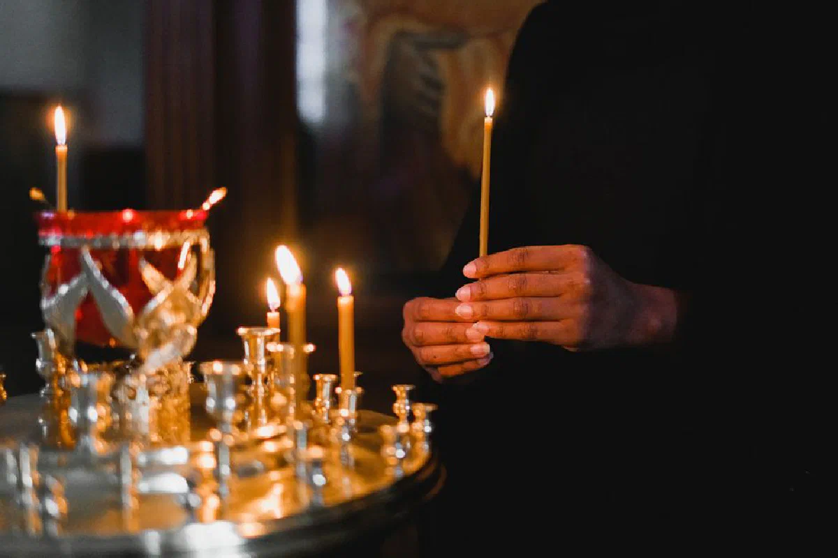 A person holding a candle in a dimly lit spiritual setting, signifying prayer and reflection.