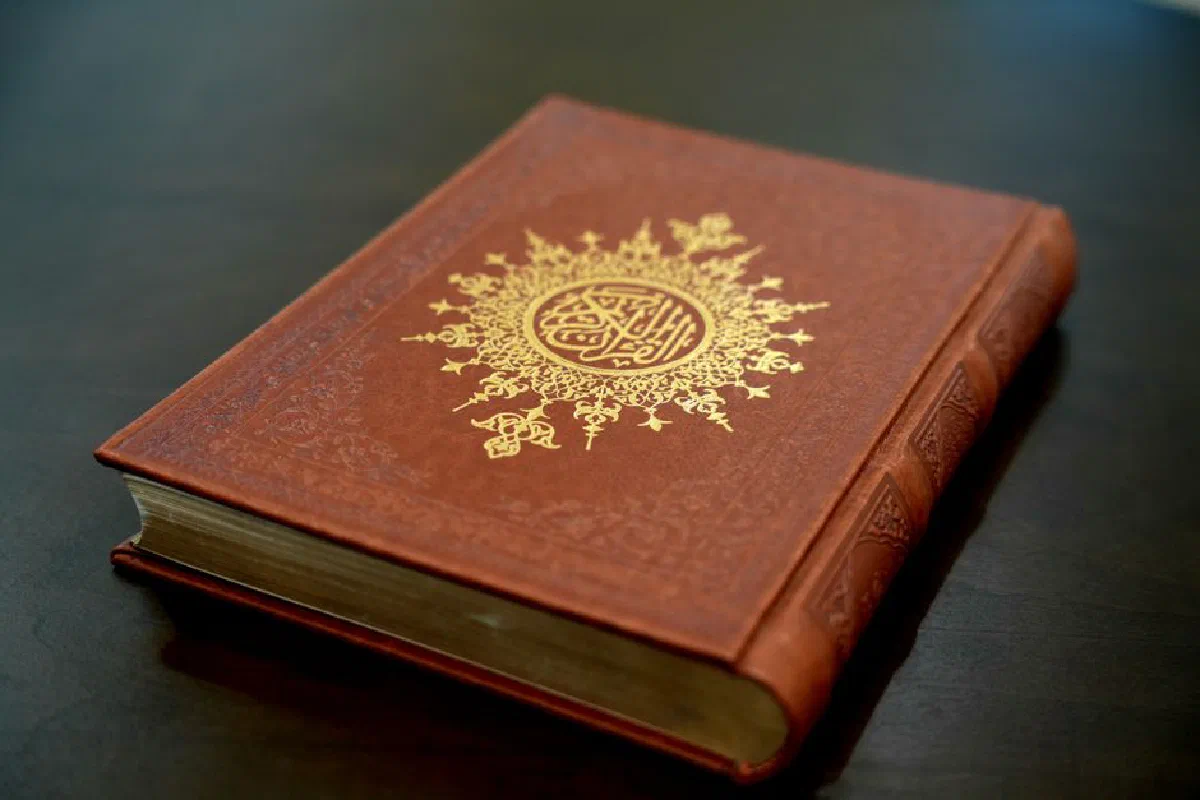 Beautiful Quran with a detailed gold design on a leather cover resting on a table.