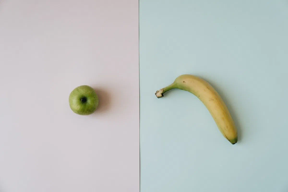 Simple top-down view of a green apple and banana on contrasting backgrounds.