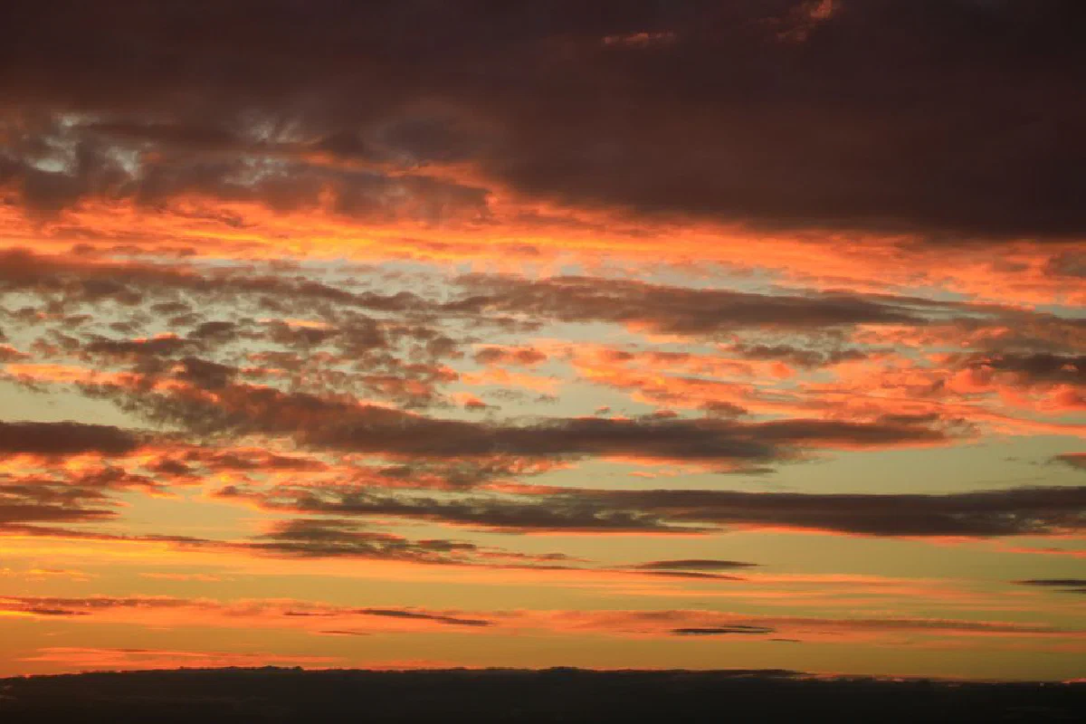 Vibrant sunset with dramatic clouds casting an orange hue across the sky.