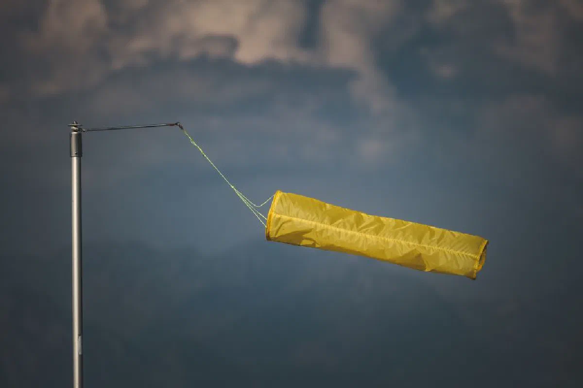An isolated yellow windsock indicating wind direction against a dark, cloudy backdrop.