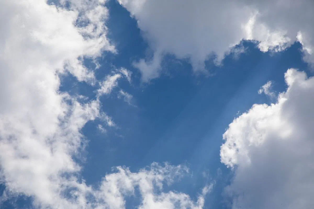 Bright blue sky filled with fluffy white clouds, radiating a tranquil vibe.
