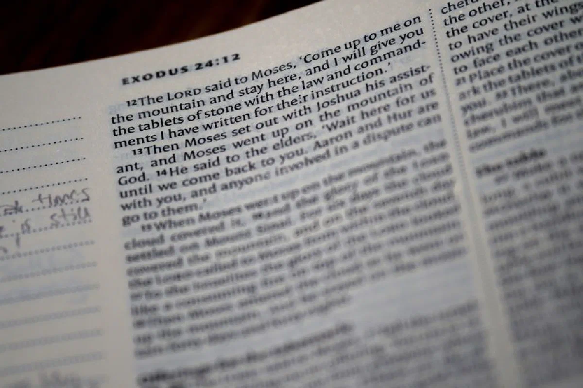 Close-up of an open Bible displaying text from Exodus 24:12.