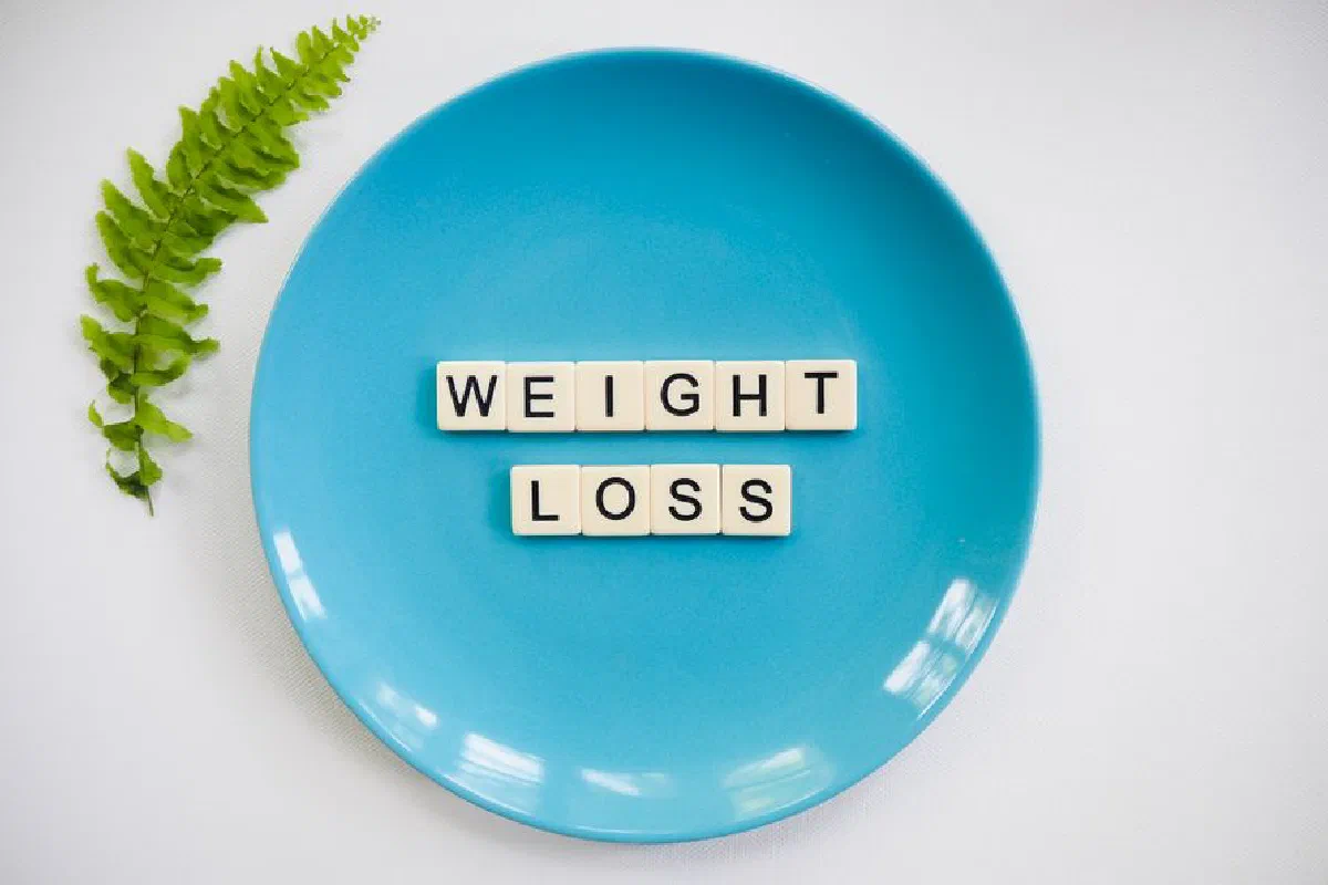 A blue plate with 'weight loss' tiles and a fern leaf on white background.