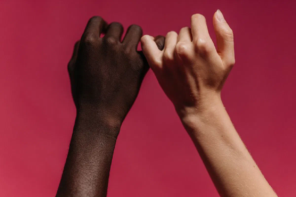 Close-up of diverse hands showing unity against a vibrant red background.