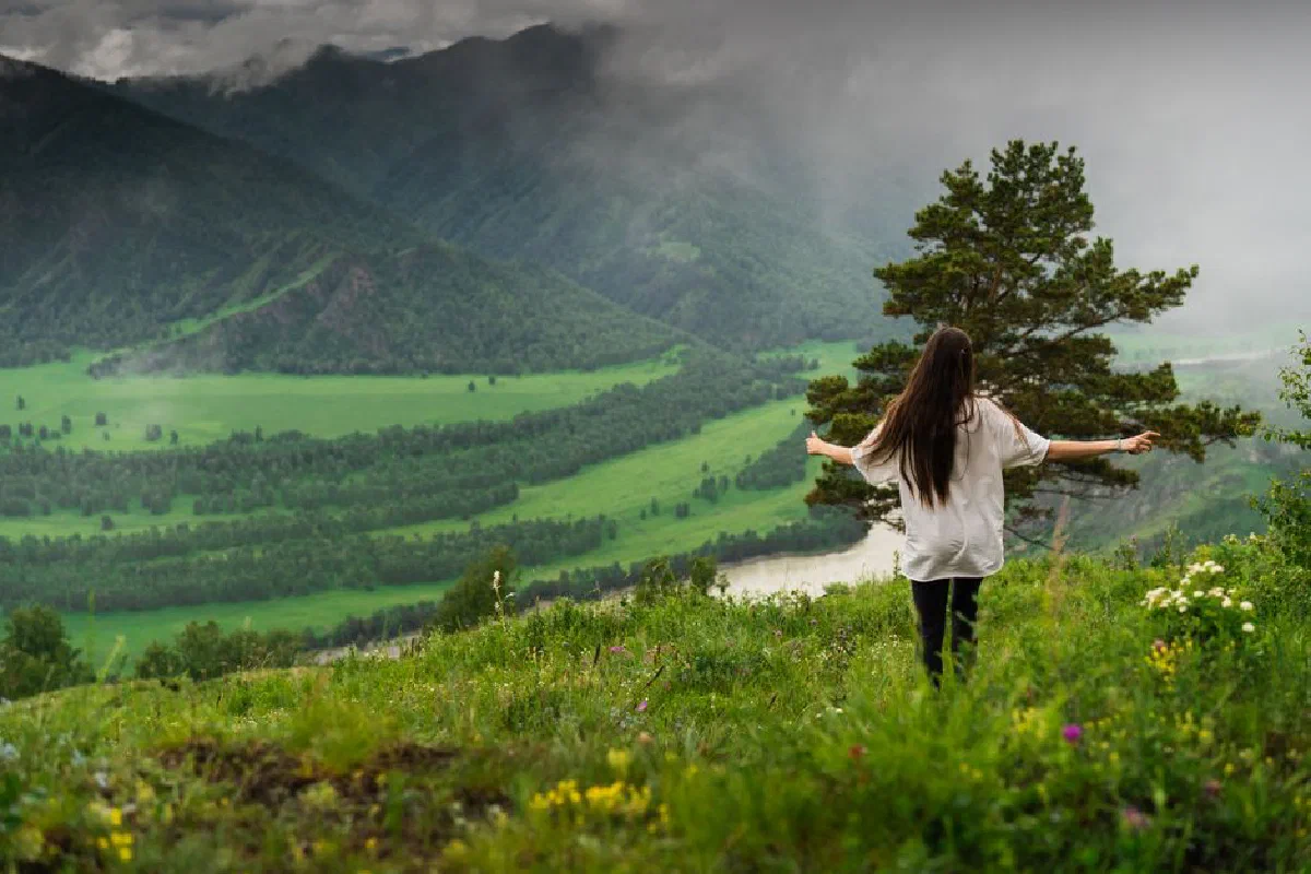 A woman stands amidst the scenic greenery of Chemal, Altai Republic, Russia.