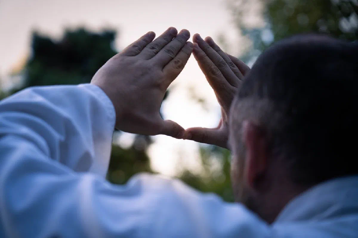 Silhouette of a man forming a triangle with hands against an outdoor backdrop in Buenos Aires.