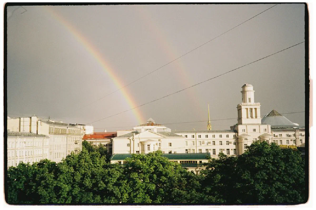 A stunning view of a double rainbow arching over classic city architecture.