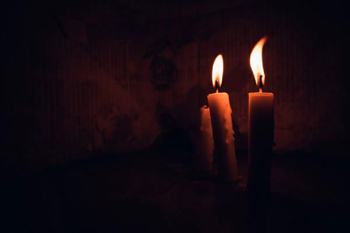 Moody close-up of two burning candles in the dark, creating a warm atmospheric ambiance.