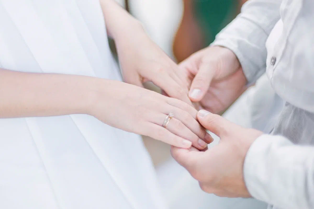A close-up shot of a bride and groom holding hands during their wedding ceremony.