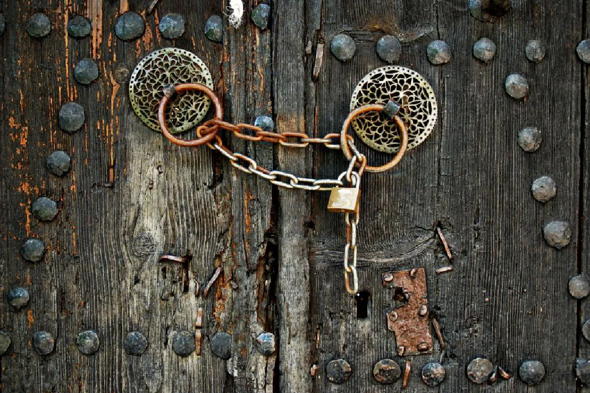 An old wooden door in Monodendri, Greece, featuring vintage metalwork and a padlock.