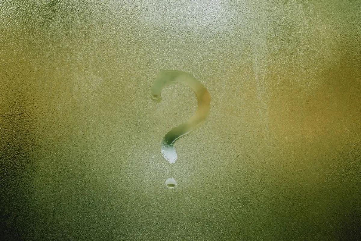 Translucent wet glass window covered with water drops with question mark on surface