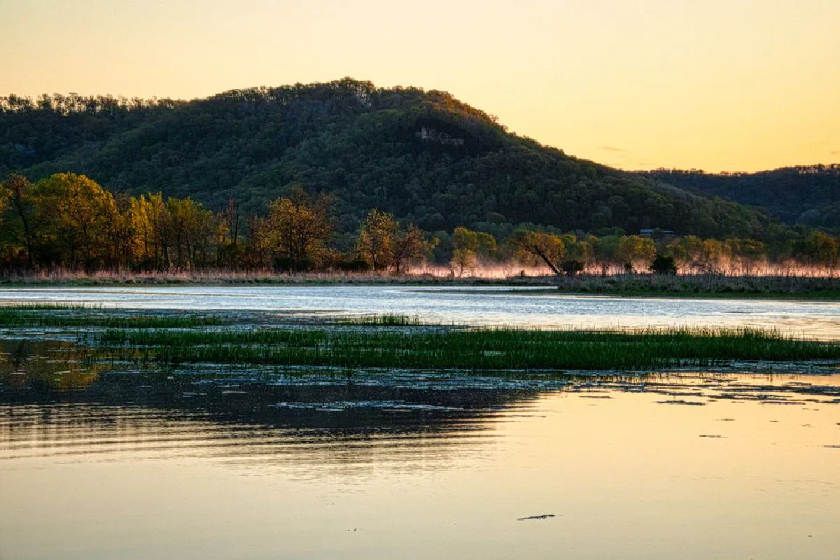 Peaceful sunrise over a river surrounded by hills and trees in Minnesota, USA.