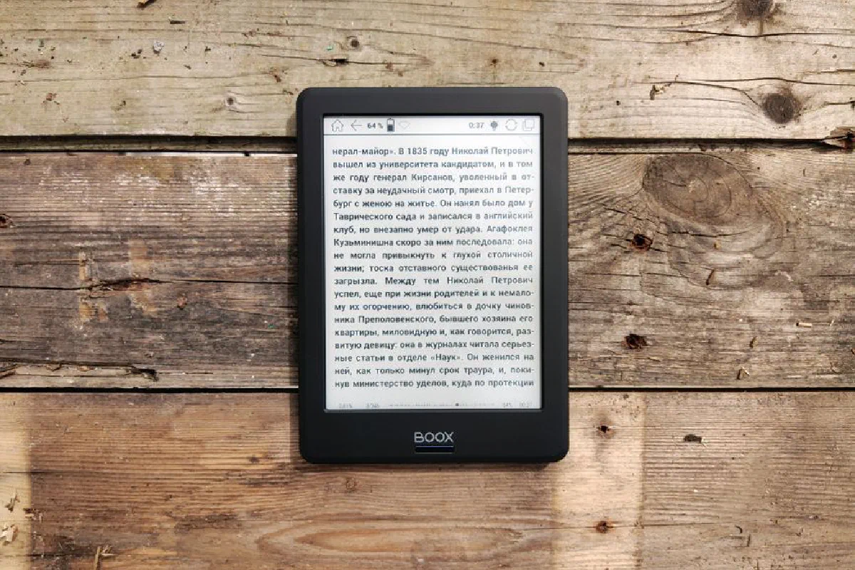 E-reader placed on a rustic wooden surface displaying text in Russian.