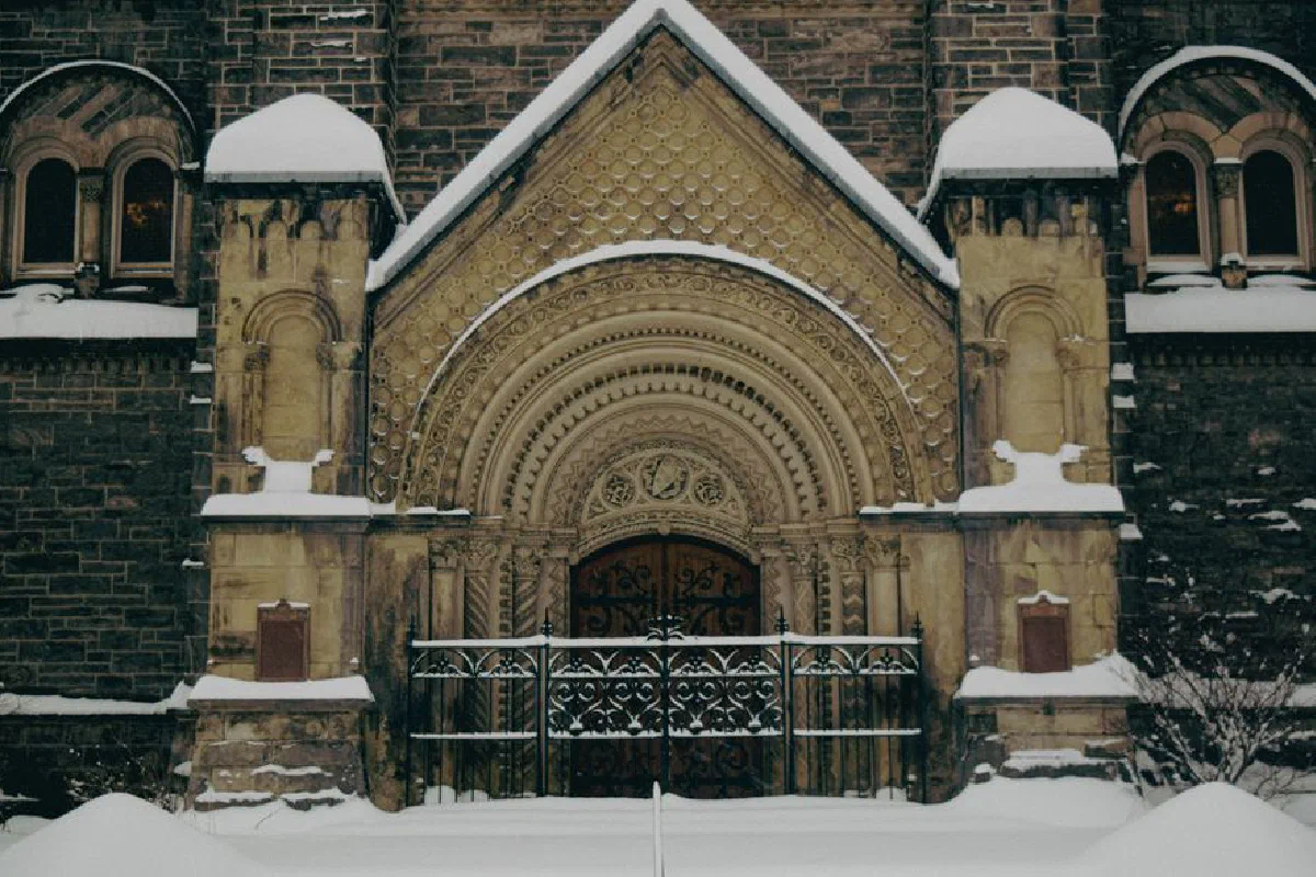 Snow-covered gothic facade at University of Toronto, displaying intricate architectural details.
