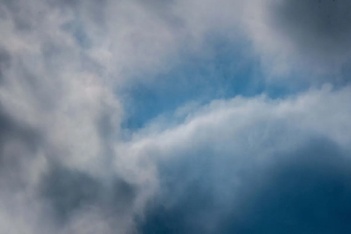 A dynamic sky filled with dramatic clouds and a glimpse of blue, portraying a sense of movement.