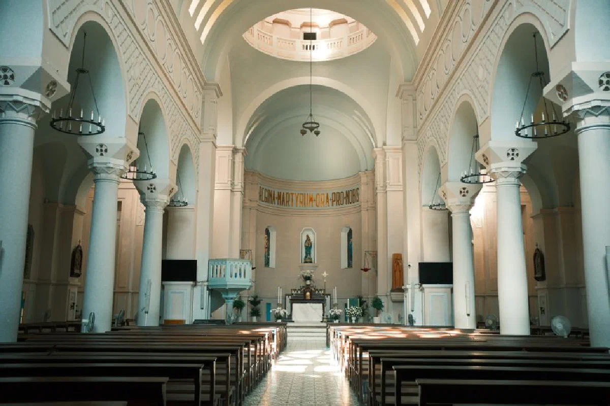 Sunlit interior of a grand Catholic church with elegant arches and stone columns.