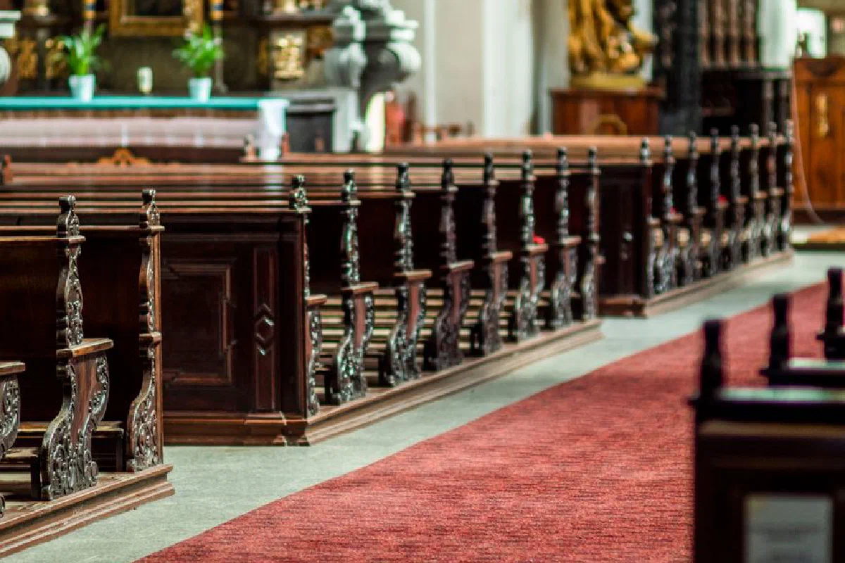 Detailed view of ornate wooden pews in an empty church interior, showcasing classical design.
