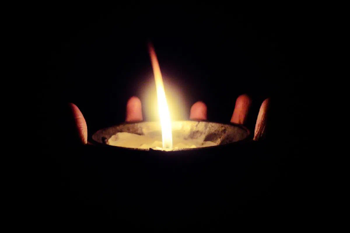 A calming close-up of a candle in dark hands, bringing warmth and serenity.