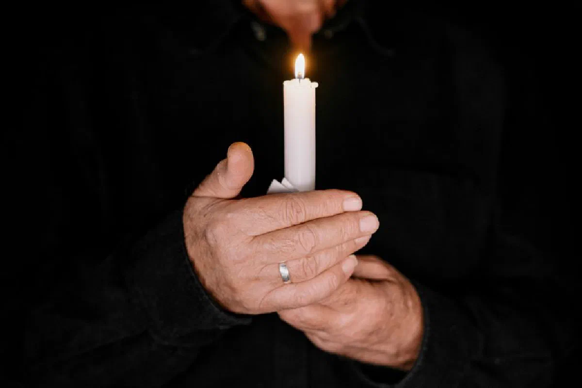 Hands holding a lit candle against a dark background, symbolizing hope and warmth.