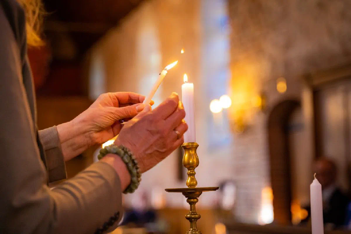A person lights a candle in a historic church, symbolizing faith and tradition.