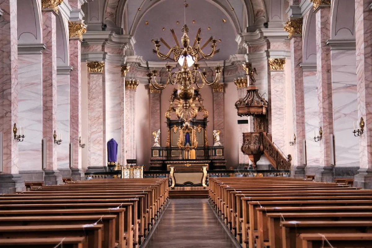 Stunning view of the Aachen Cathedral's ornate interior with golden chandeliers and wooden pews.