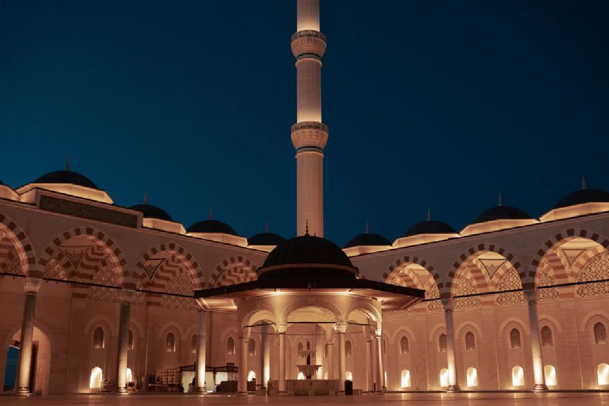 Beautifully lit mosque and minaret under a dark, clear night sky in İstanbul.