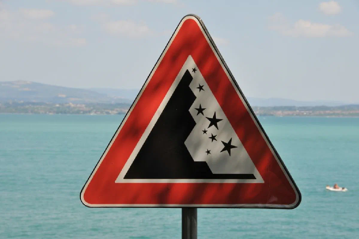 A rockfall warning sign with Lake Garda in the background, Sirmione, Italy.