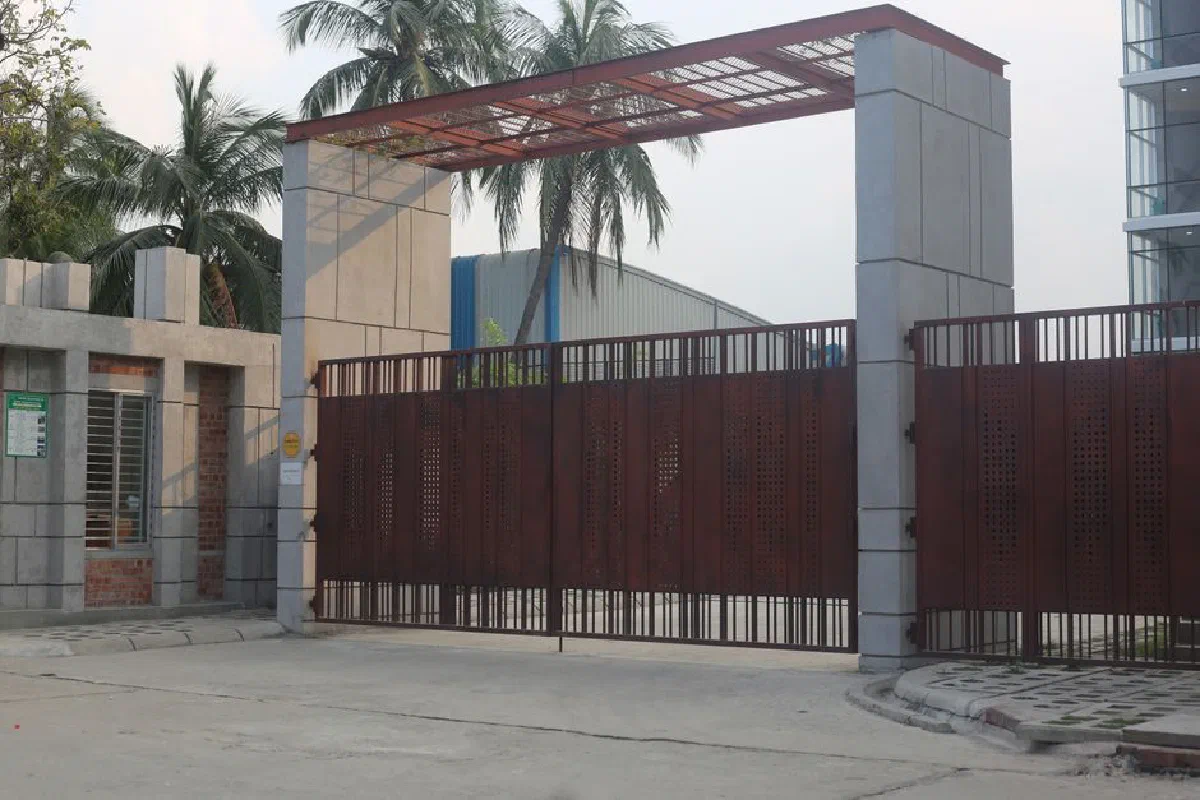 A large automated iron gate as the entrance to a modern urban building, surrounded by palm trees.