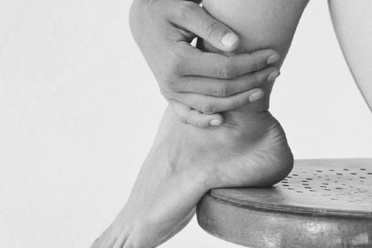 Monochrome image capturing the elegance of a woman's feet and hands on a stool.
