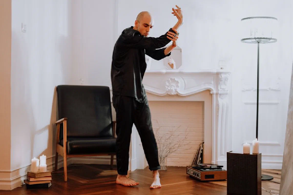A male dancer performs contemporary dance indoors, showcasing graceful moves and expression in a stylish room.