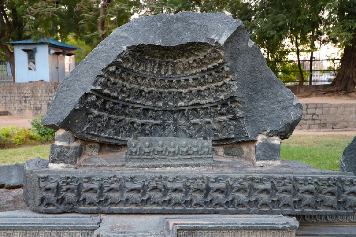 Detailed ancient stone carving depicting intricate patterns, photographed in a quaint outdoor setting.