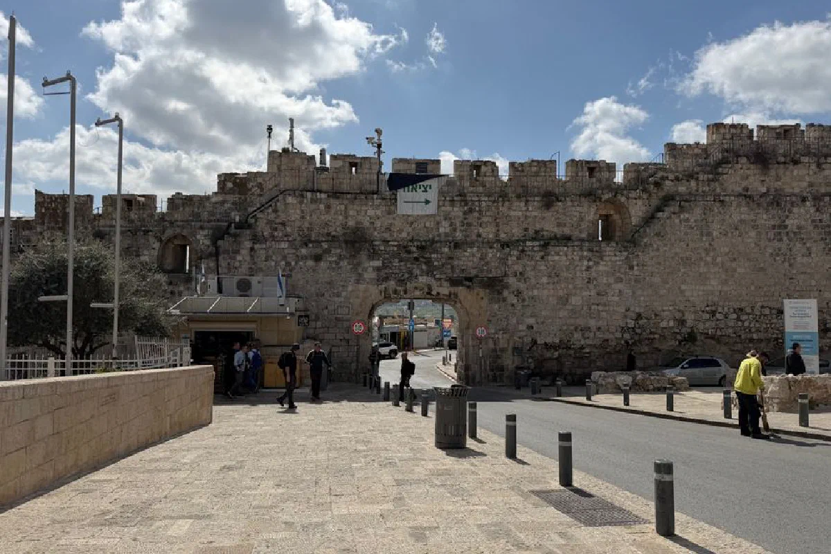 View of historic Jaffa Gate in Jerusalem's Old City with pedestrians and clear blue sky.