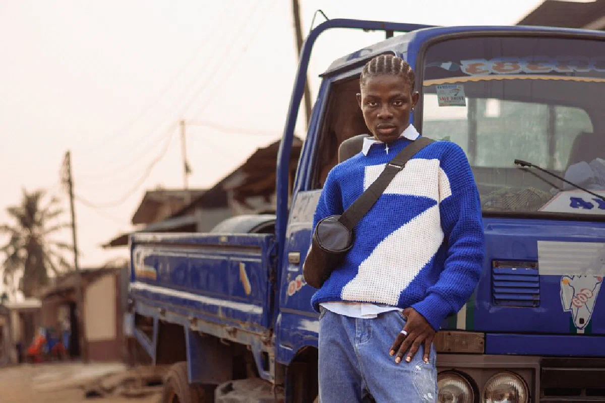 Stylish young man posing by a blue truck in a Lagos street, Nigeria.