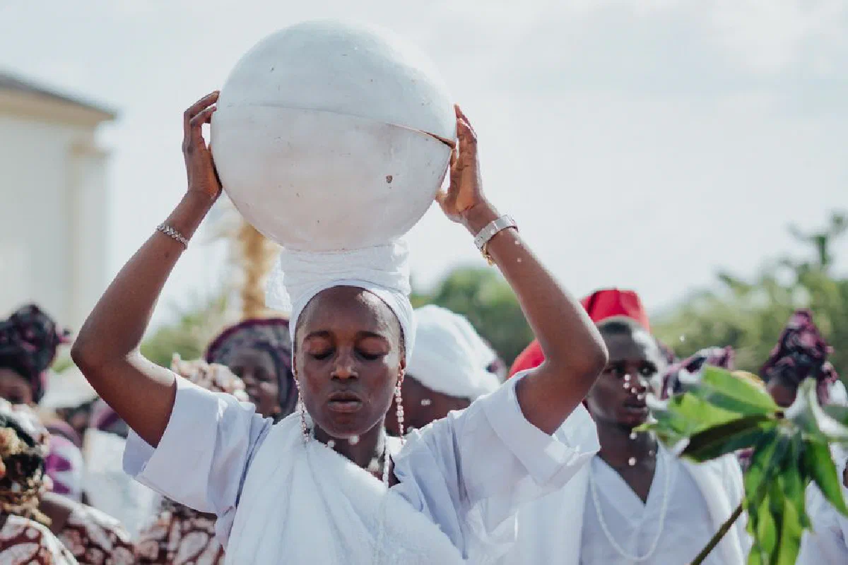 A ceremonial procession featuring individuals in traditional white attire, highlighting cultural heritage.