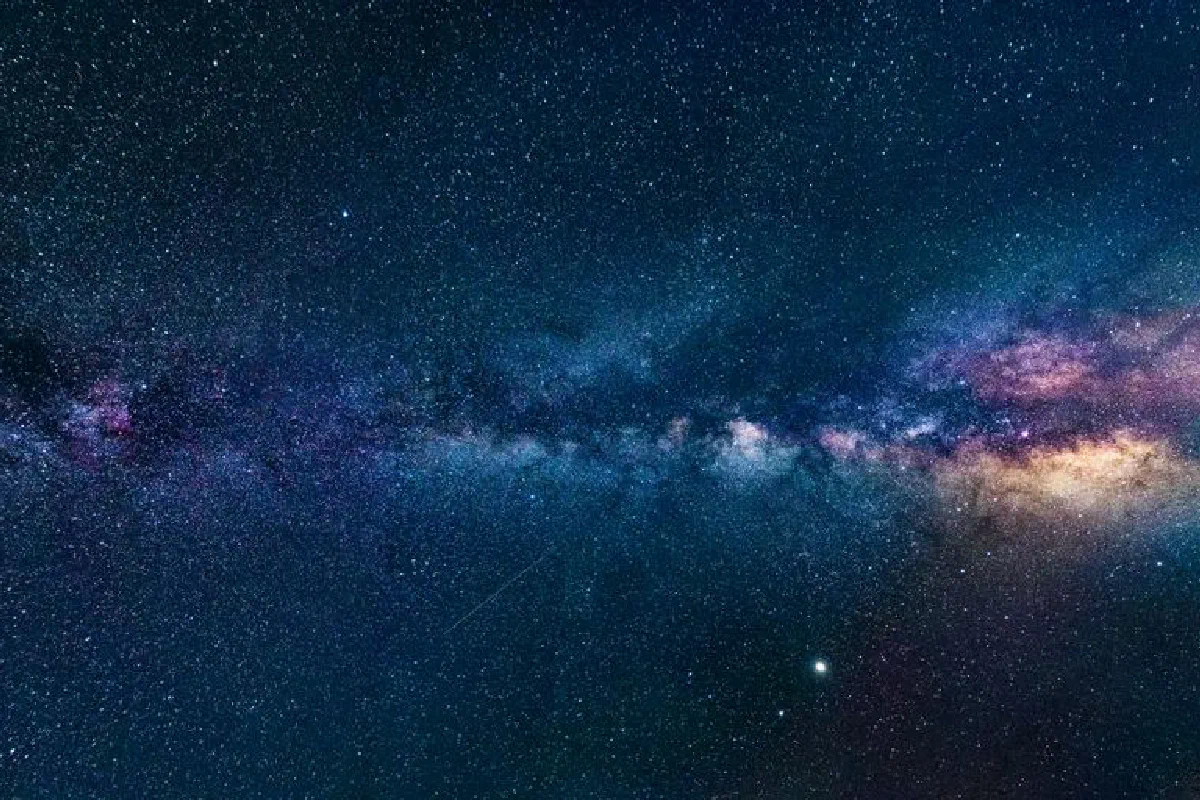Capture of the Milky Way galaxy stretching across the dark night sky, filled with stars.