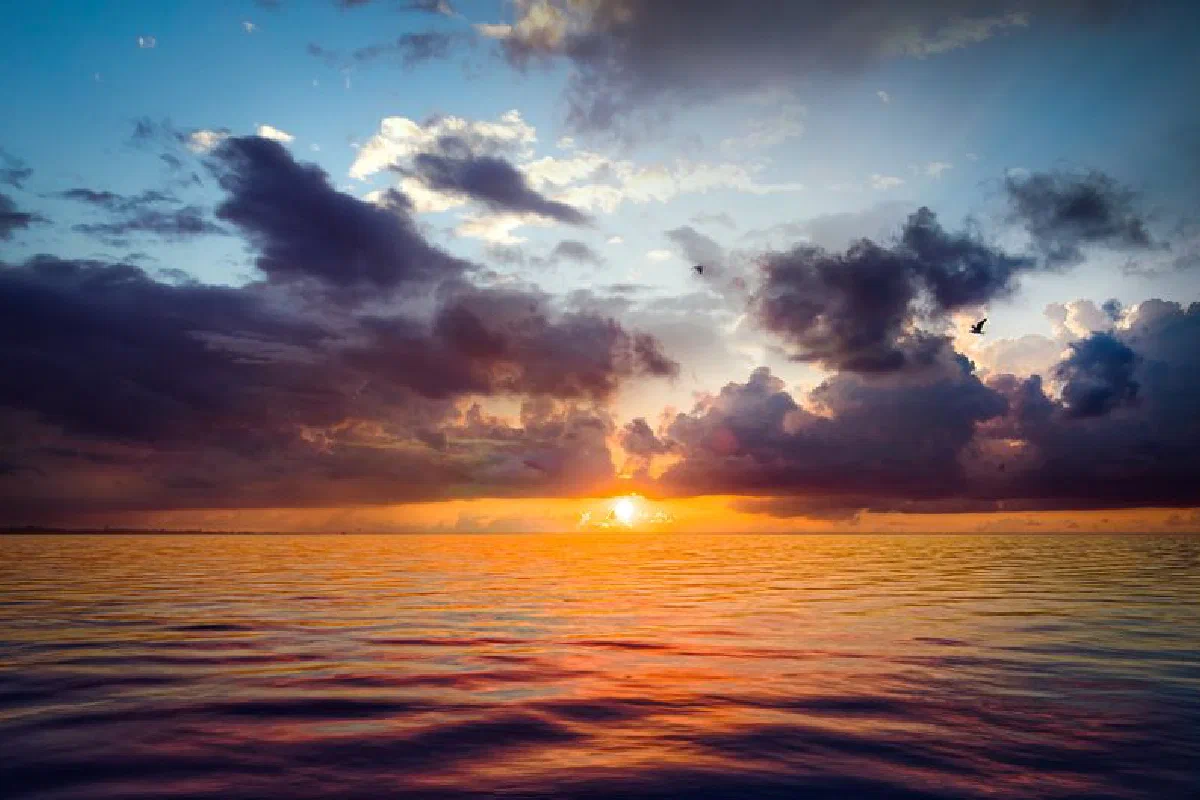 A captivating ocean sunset with dramatic clouds, vibrant colors, and serene water reflections.