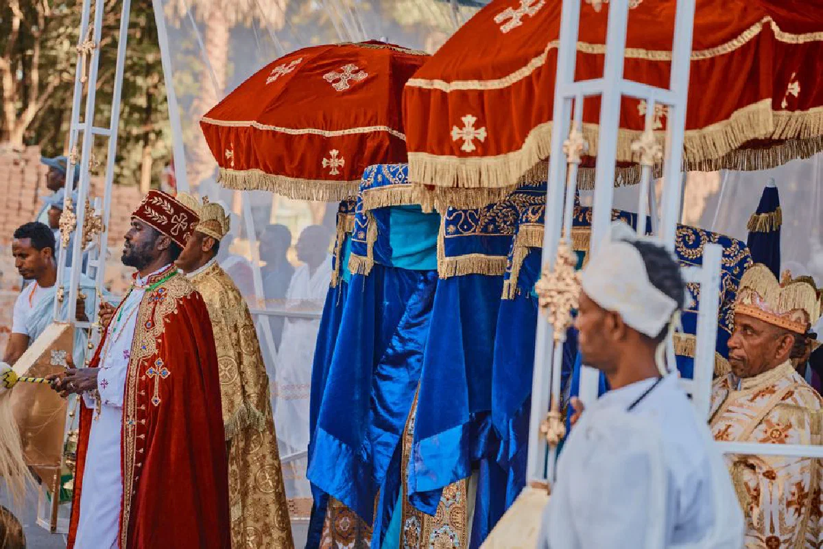Vibrant Ethiopian religious procession featuring ornate umbrellas and traditional attire.