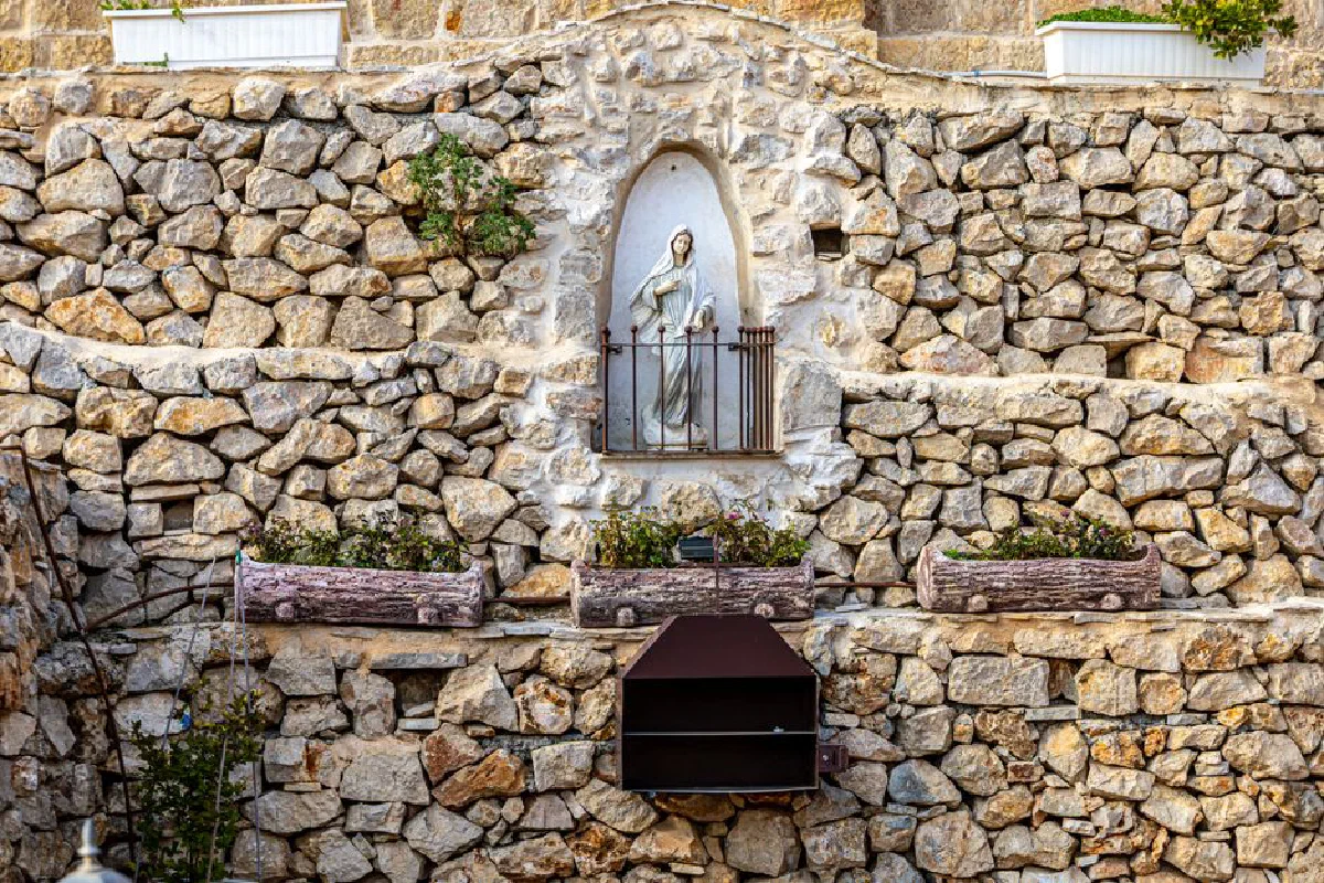Stone wall with a religious statue set in Bethlehem, showcasing rustic architecture and plant accents.