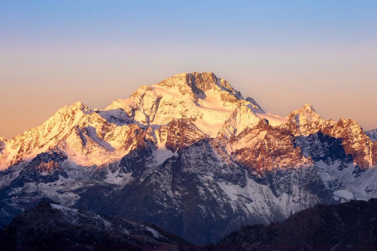 Captivating sunrise view of snow-covered mountain peaks with a golden glow.