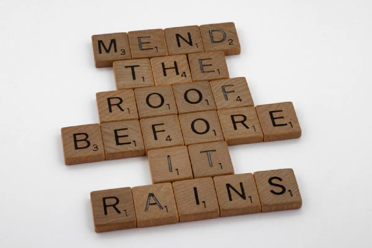 Scrabble tiles on a white background with the phrase 'Mend the roof before it rains'.