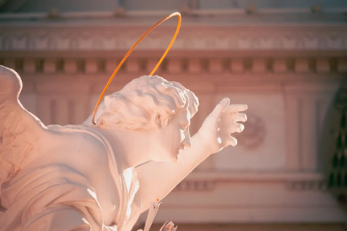 Close-up of an angel statue with halo, bathed in warm sunset light, evoking serenity and spirituality.