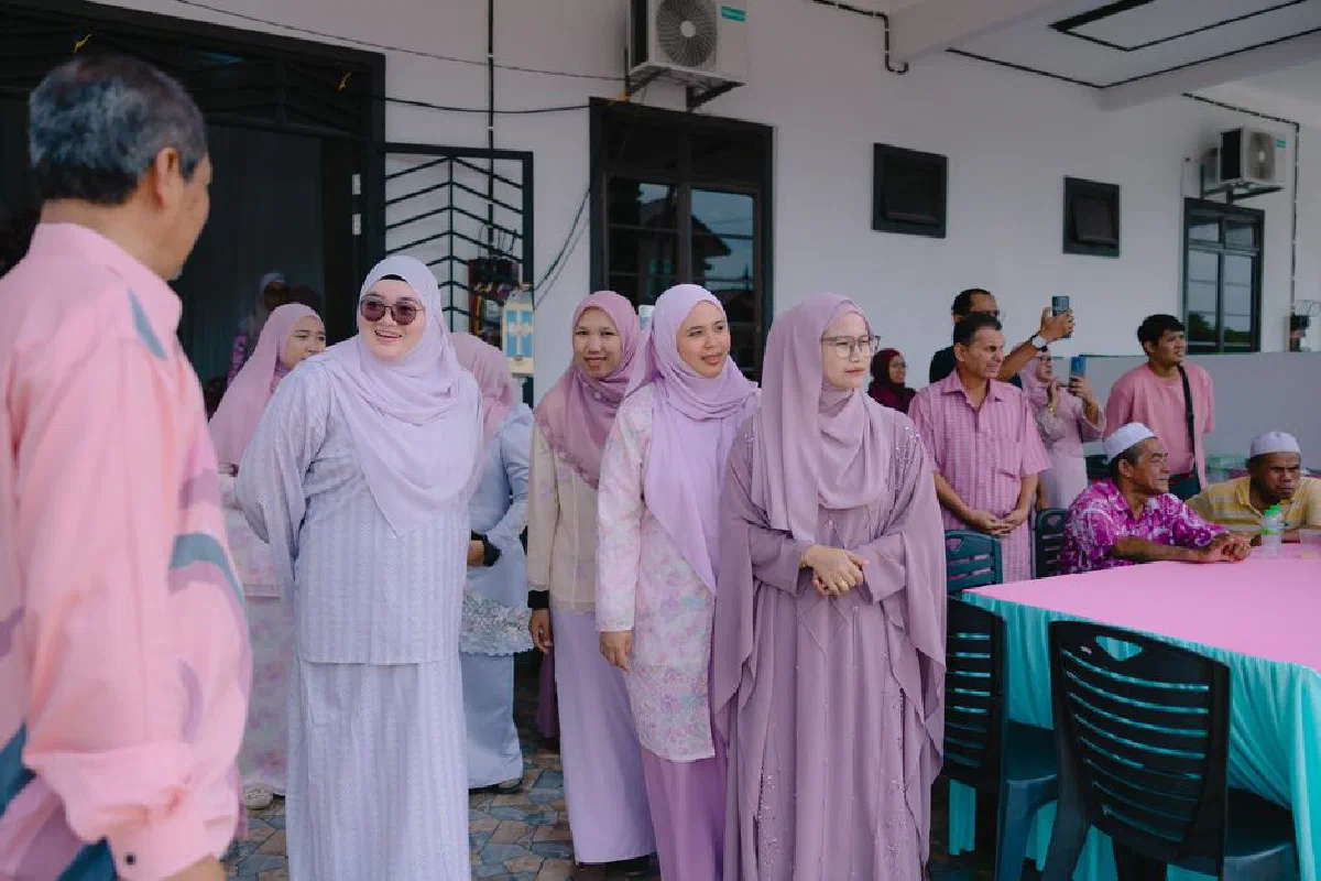 A diverse group of people in traditional attire gather outdoors for a social event.