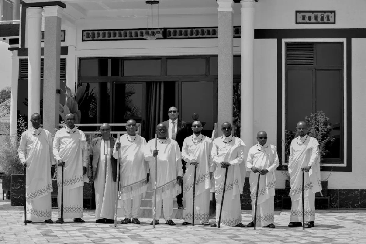 A group of men in traditional Rwandan attire stands outside a building, exuding cultural heritage.
