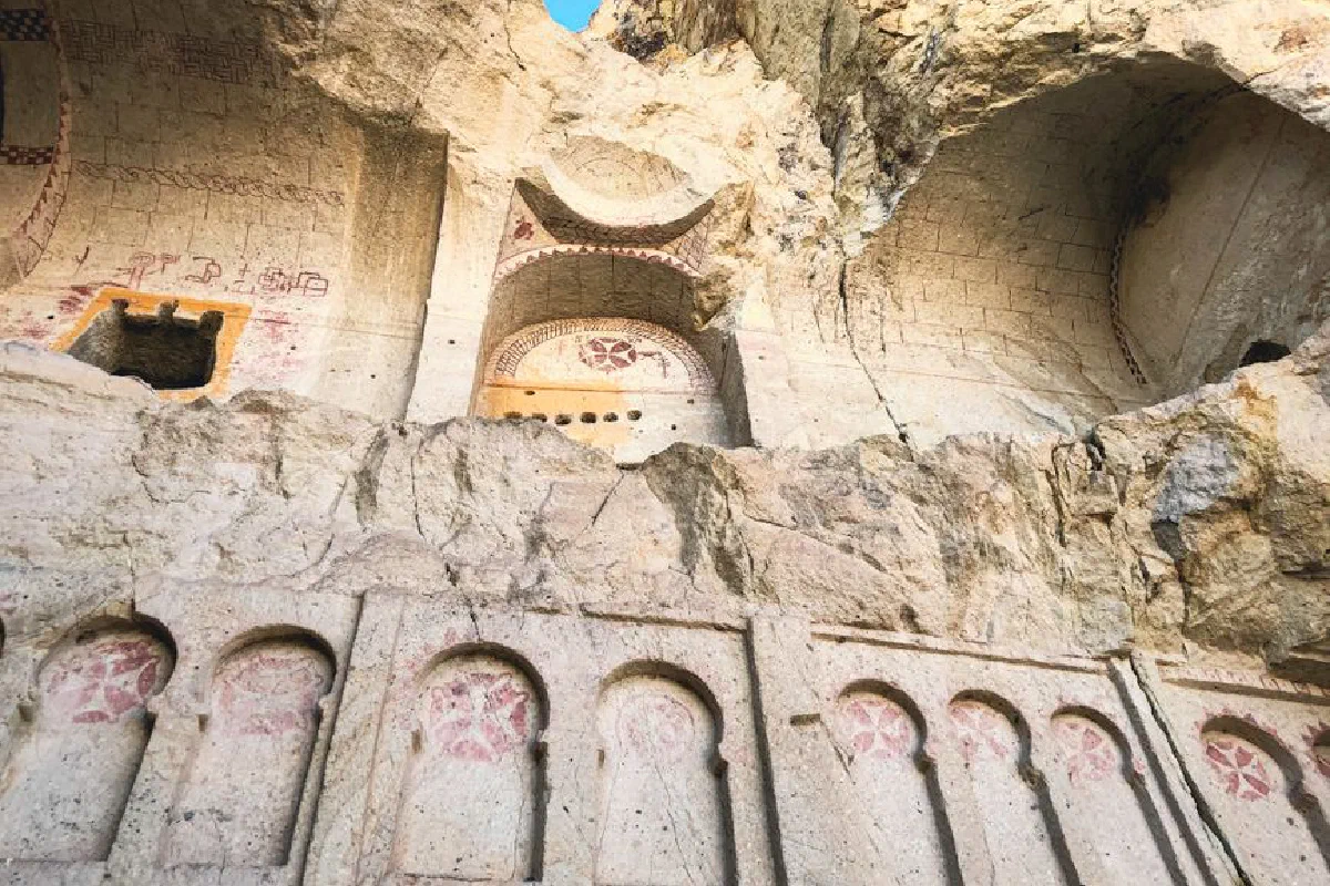 Low-angle shot of ancient rock carvings and frescoes in a cave, showcasing historical art.
