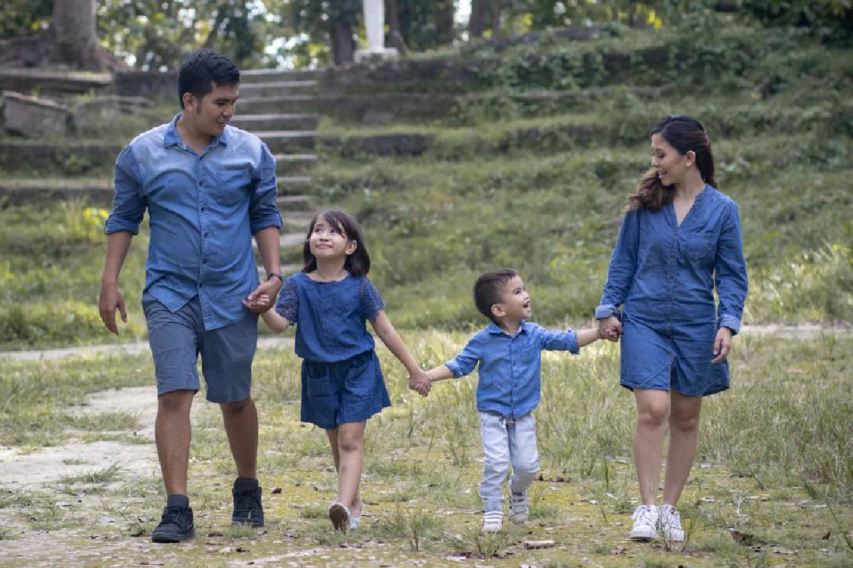 Family enjoying a walk together in a lush outdoor setting, sharing joyful moments.