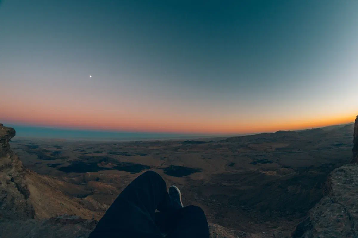 Experience the breathtaking view of a colorful sunset over the Mitzpe Ramon crater in Israel.