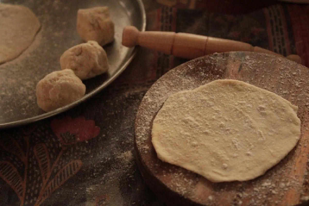 A wooden board with rolled dough in a cozy kitchen setting.