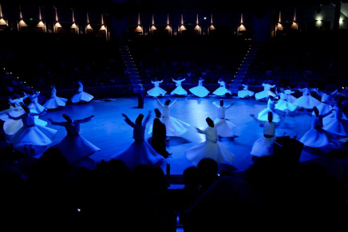Mesmerizing dervish dancers performing a traditional dance on stage under blue lights.